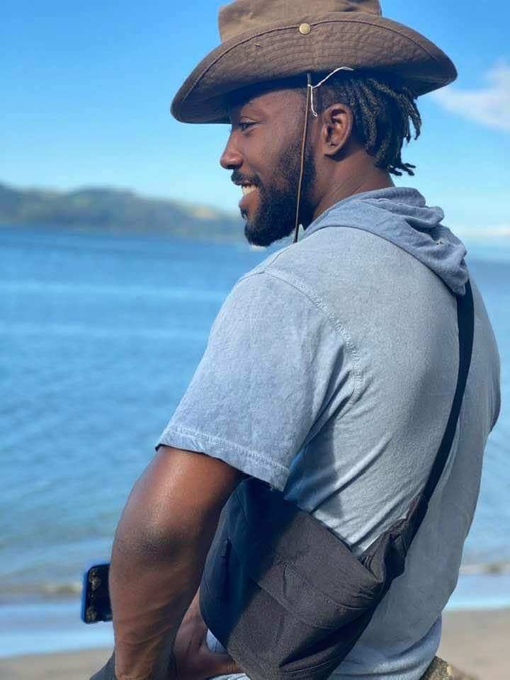 malik wears a cowboy hat near the shore.